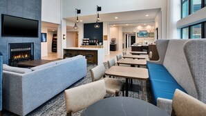 En modern hotellobby med en öppen spis, sittgrupper och en bar.