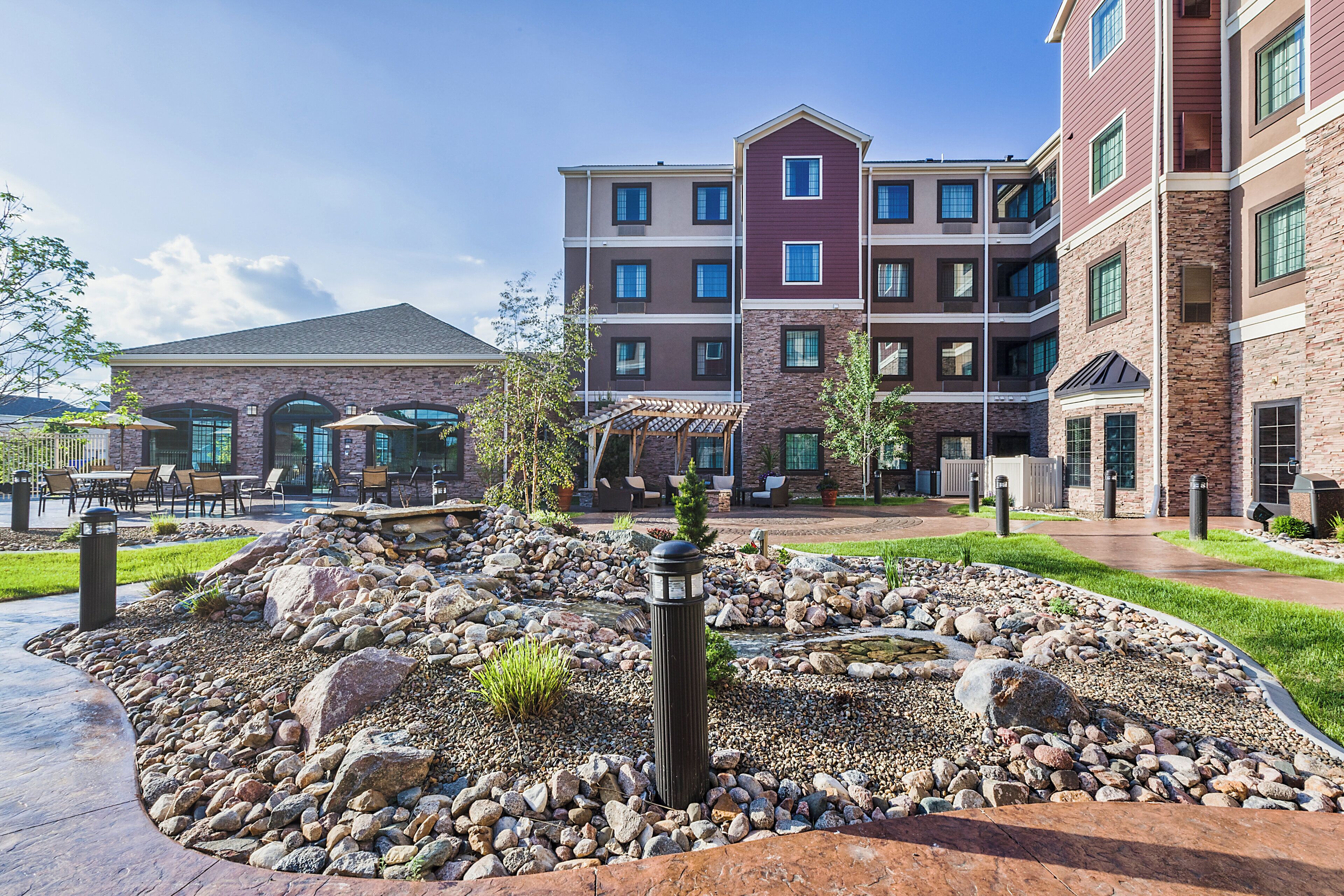 A multi-story hotel with a landscaped courtyard featuring a rock garden and outdoor seating.