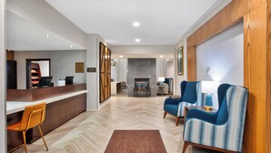 En modern hotellobby med en receptionsdisk, en sittgrupp och en öppen spis.