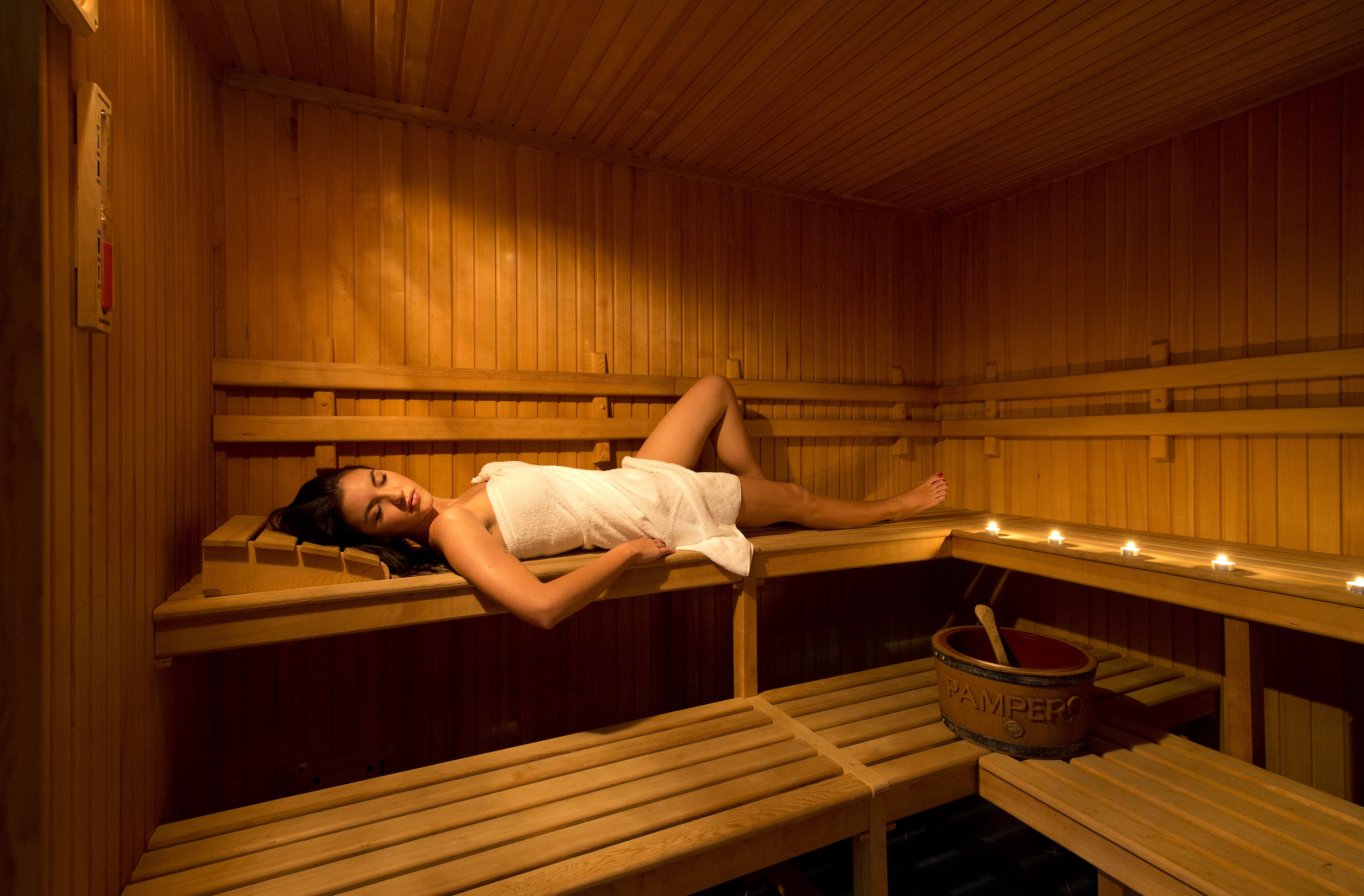 A sauna with wooden benches and a person lying on one.