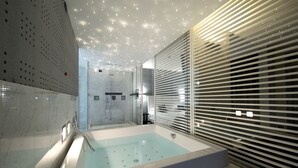 Un baño moderno con una bañera grande, una zona de ducha y mampara de cristal.