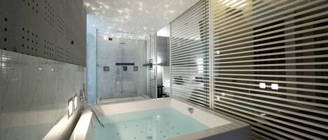 A modern bathroom with a large bathtub, a shower area, and a glass-enclosed shower.