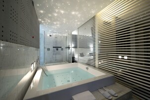 Un baño moderno con una bañera grande, una zona de ducha y mampara de cristal.