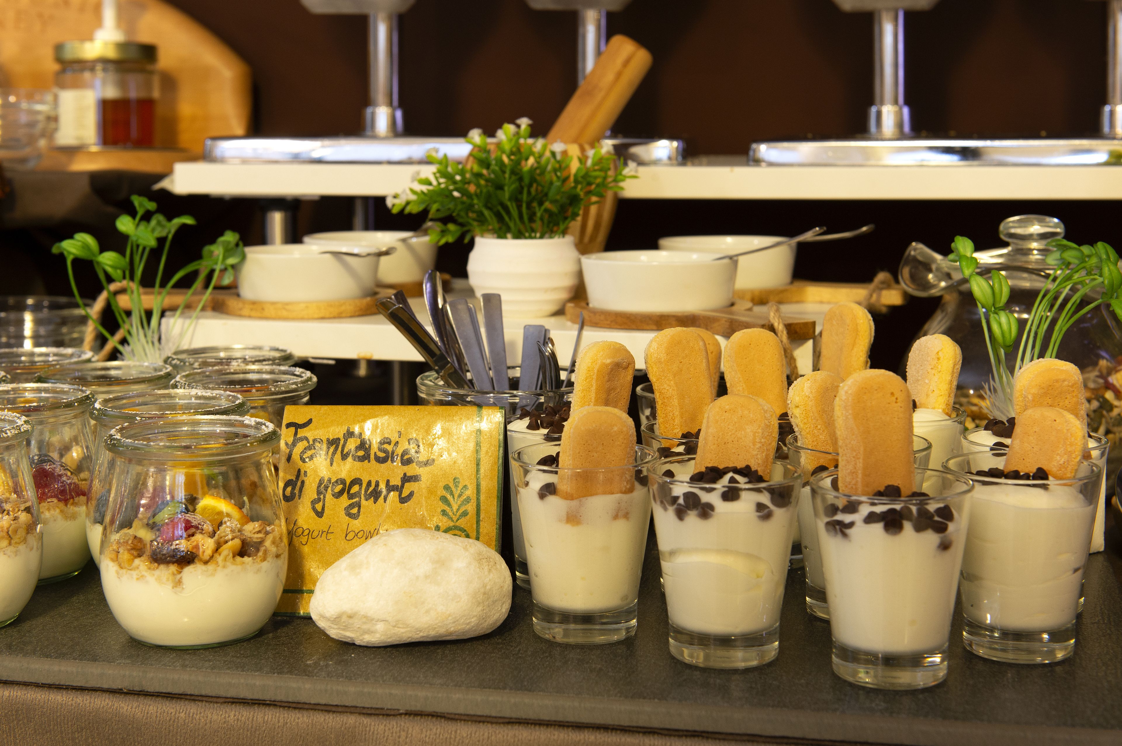 Une variété de desserts, notamment des yaourts en verrine et des gressins, présentés sur un comptoir.