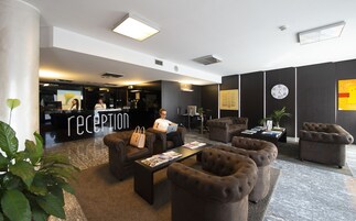 Un área de recepción con mostrador, asientos y un reloj en la pared.