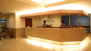 A reception desk at Okinawa Un Plaza Hotel with a counter, a phone, and a small plant. - Okinawa Sunplaza Hotel (Naha)