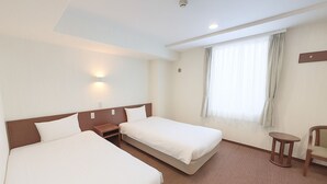 A hotel room with two beds, a small table, a chair, and a window with curtains. - Smile Hotel Namba (Osaka)