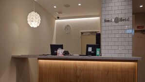 A reception desk with a wooden panel design, a clock on the wall, and a sign for Smile Hotel. - Smile Hotel Namba (Osaka)