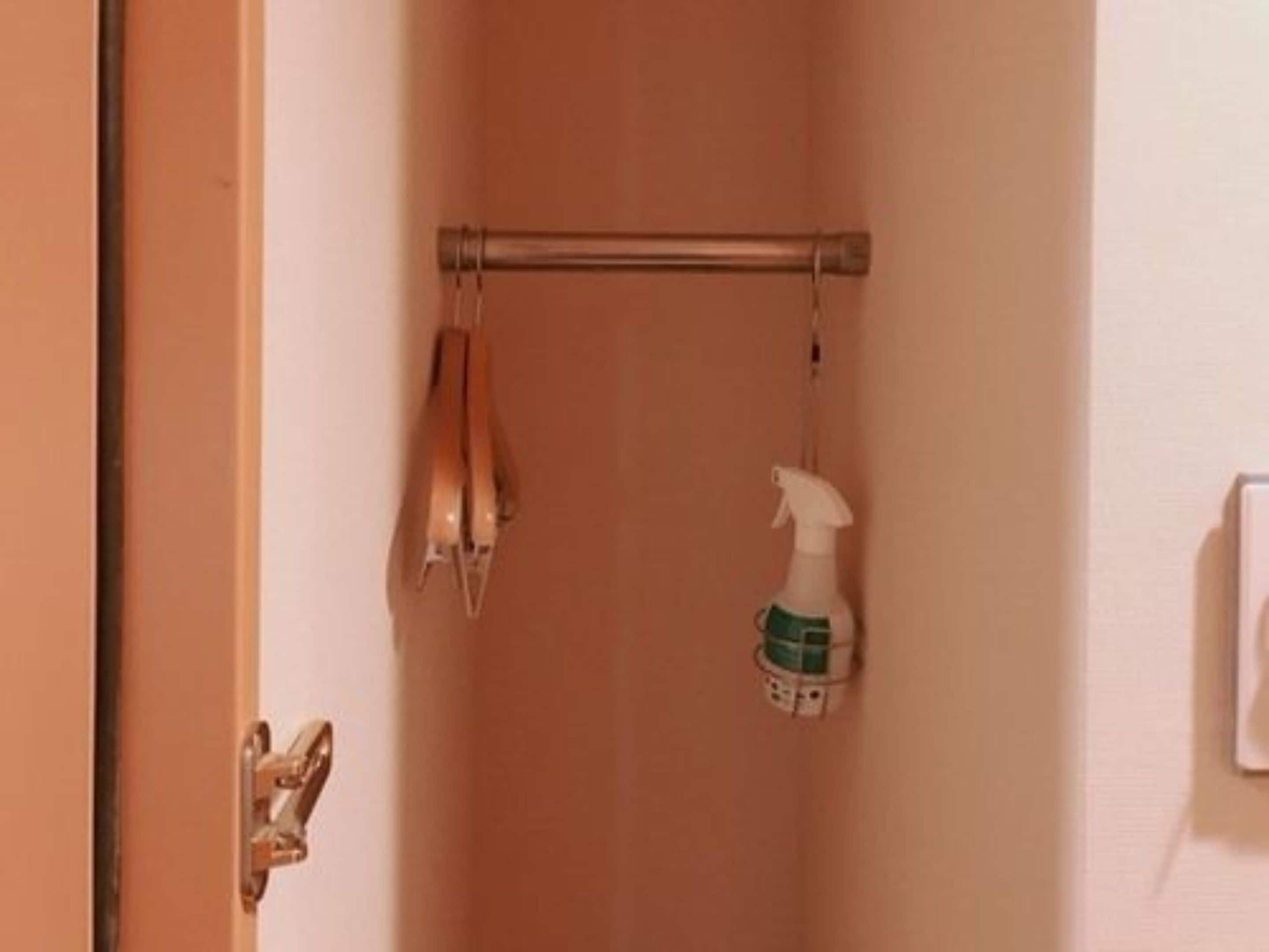 A bathroom with a towel rack, a shower curtain rod, and a spray bottle.