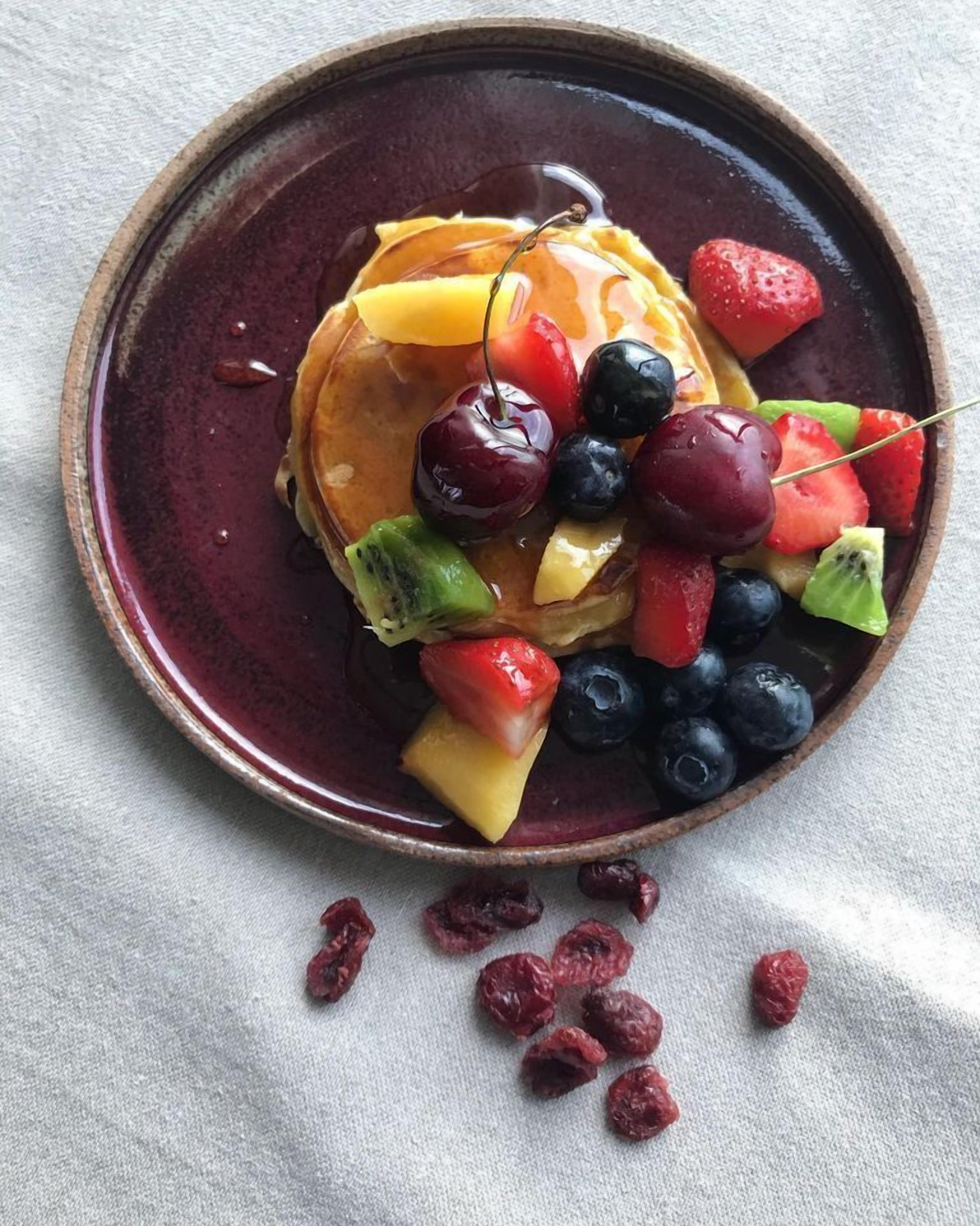 A plate of pancakes topped with various fruits and syrup.