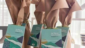 Three paper bags with tags from Le Nove bike hotel, featuring a recommended bike and cycling tour.