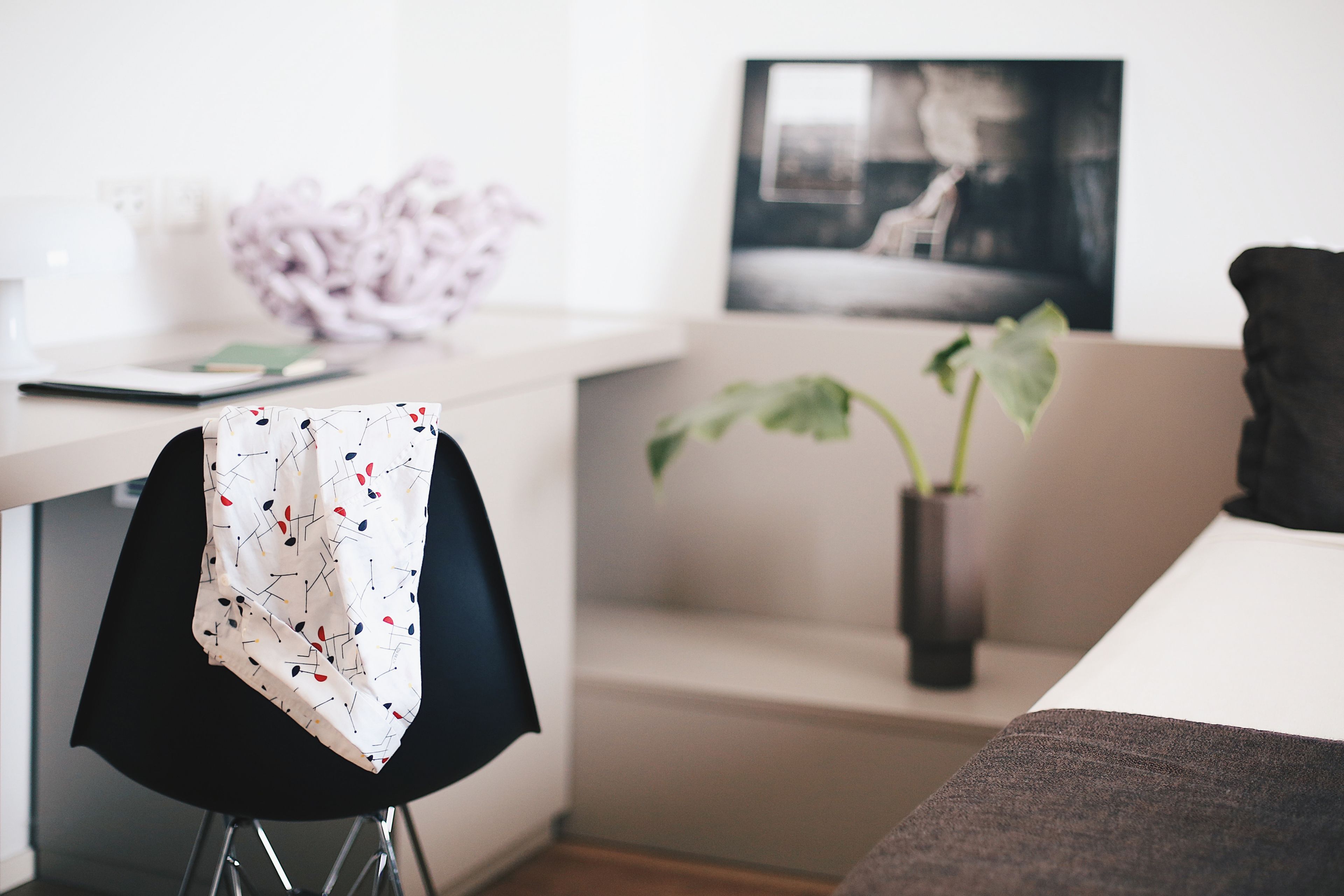 A modern room with a desk, a chair, a couch, and a potted plant.