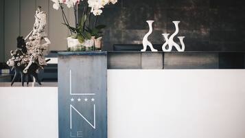 A reception desk with a modern design, featuring a logo and a decorative plant arrangement.