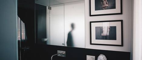 Un baño moderno con un espejo grande, un lavabo blanco y dos cuadros enmarcados en la pared.