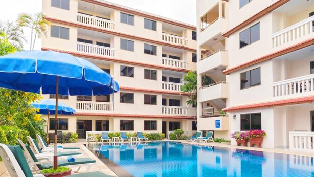 Un hotel con piscina, varios balcones y sillones de descanso.
