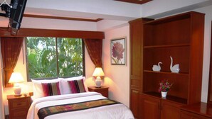 Un dormitorio con una cama, dos mesitas de noche con lámparas, un armario de madera y una ventana con cortinas.