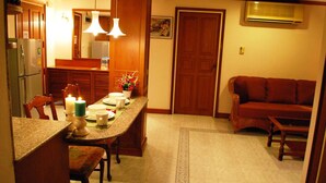 Una cocina con armarios de madera, una mesa de comedor con sillas, un sofá rojo y una alfombra estampada.