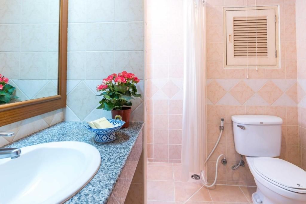 A bathroom with a sink, toilet, shower, and a mirror.