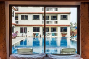 A hotel room with a view of a swimming pool, a balcony, and a building with multiple windows. - The Residence Garden (Pattaya)