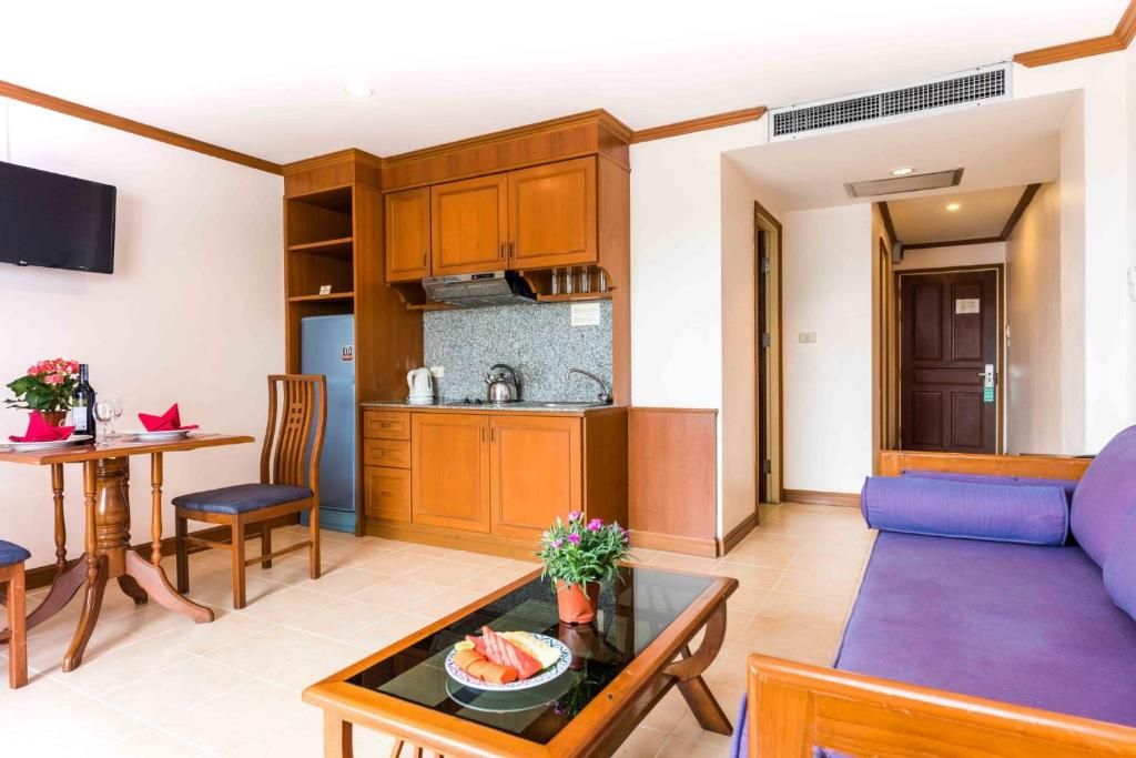 Un espace de vie compact comprenant un coin cuisine, un coin repas avec une table et des chaises, et un coin salon avec un canapé.