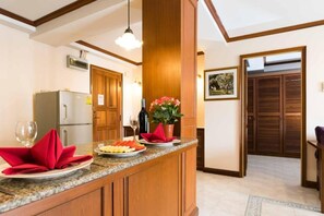 Eine Küche mit einer Granitabdeckung, Holzschränken, einem Kühlschrank, einer Weinflasche und einem Blumentopf.