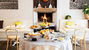Una habitación acogedora con chimenea, una mesa de comedor con gran variedad de comida y dos sillas.