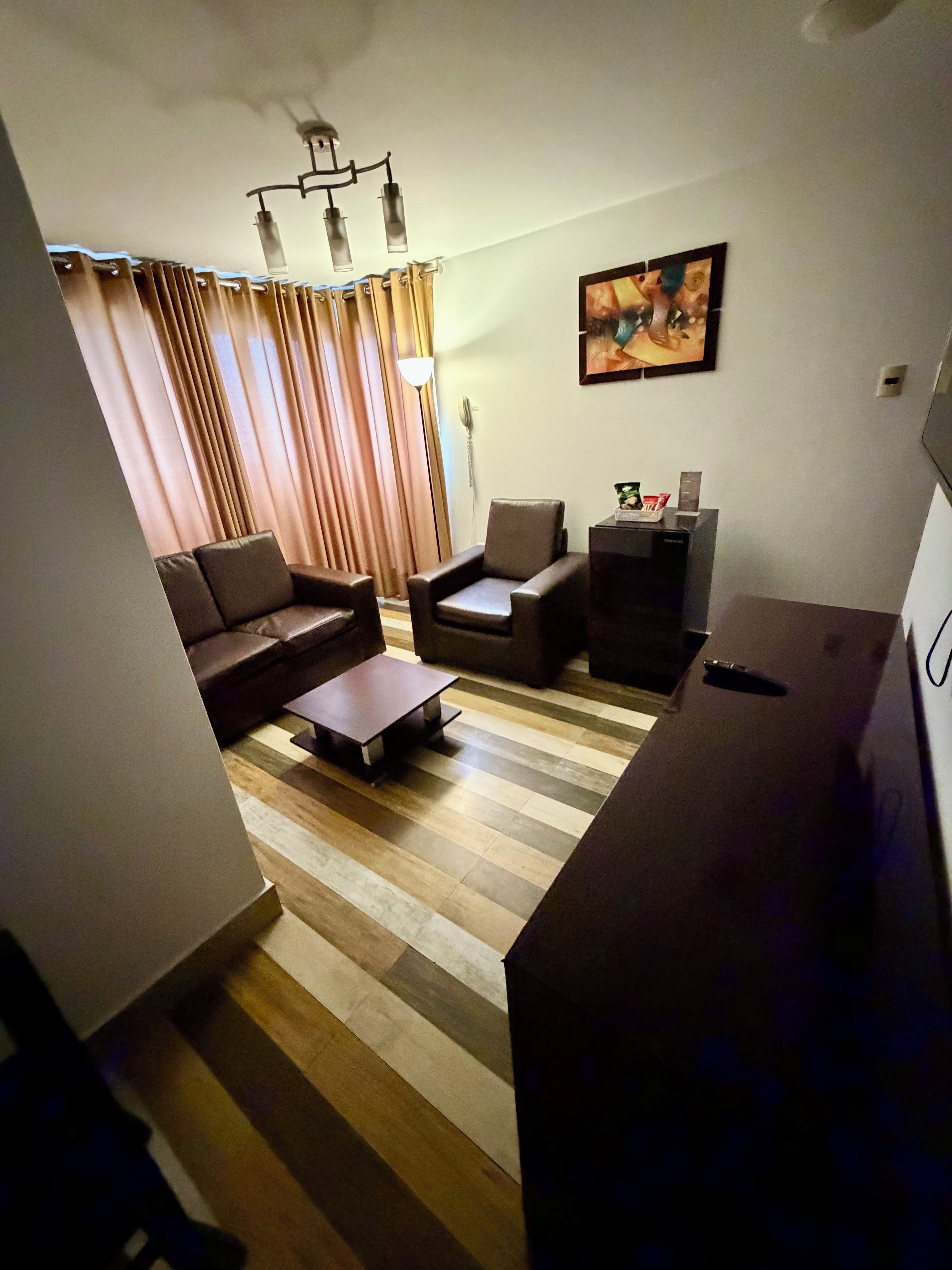 A living room with a sofa, armchair, coffee table, and a television.