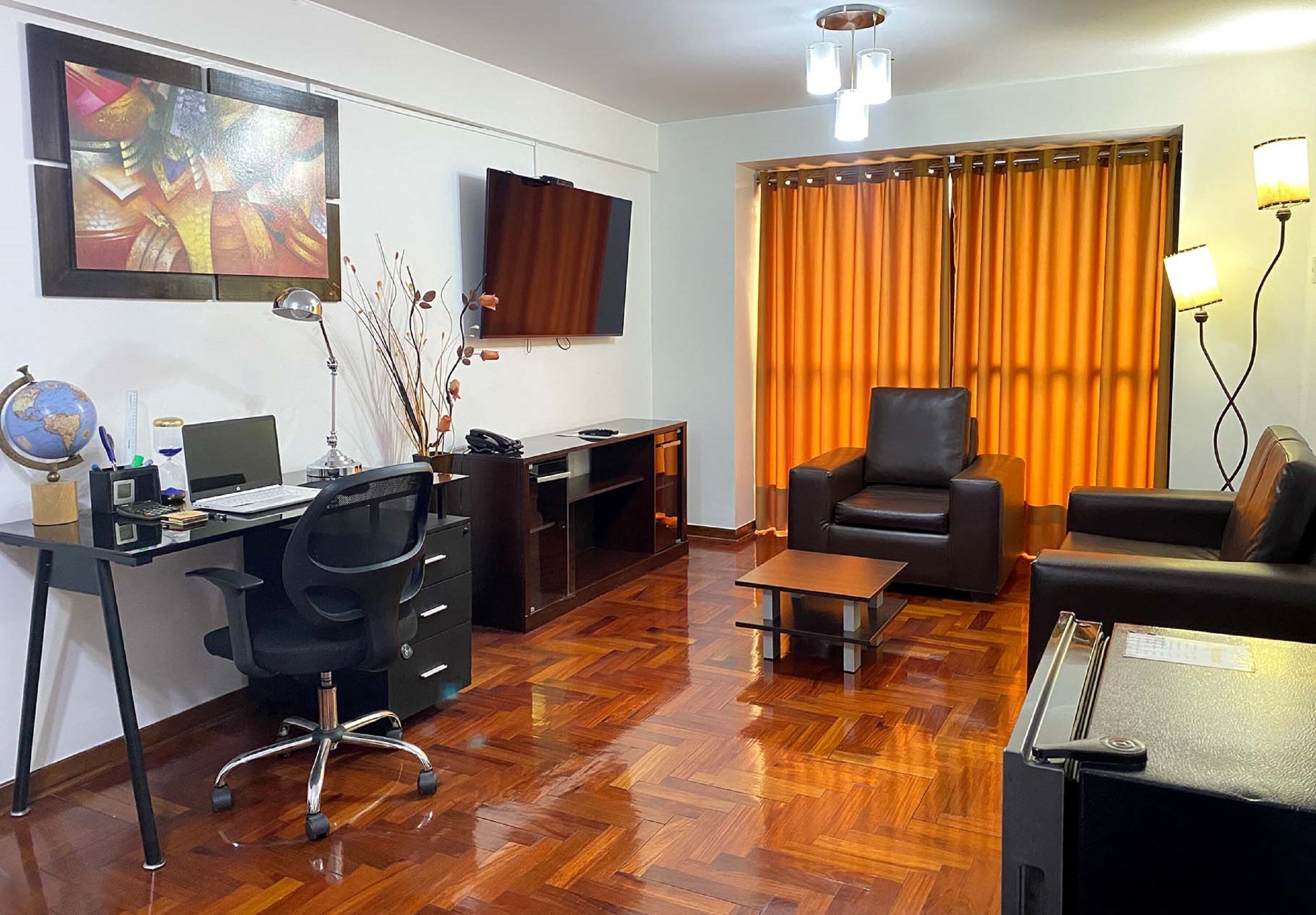 Een moderne woonkamer met een houten visgraatvloer, een zwarte leren bank, een zwarte leren fauteuil, een houten salontafel, een zwart bureau met een computer, een wereldbol en een televisie.