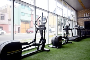 Uma academia com equipamentos de exercício e amplas janelas.