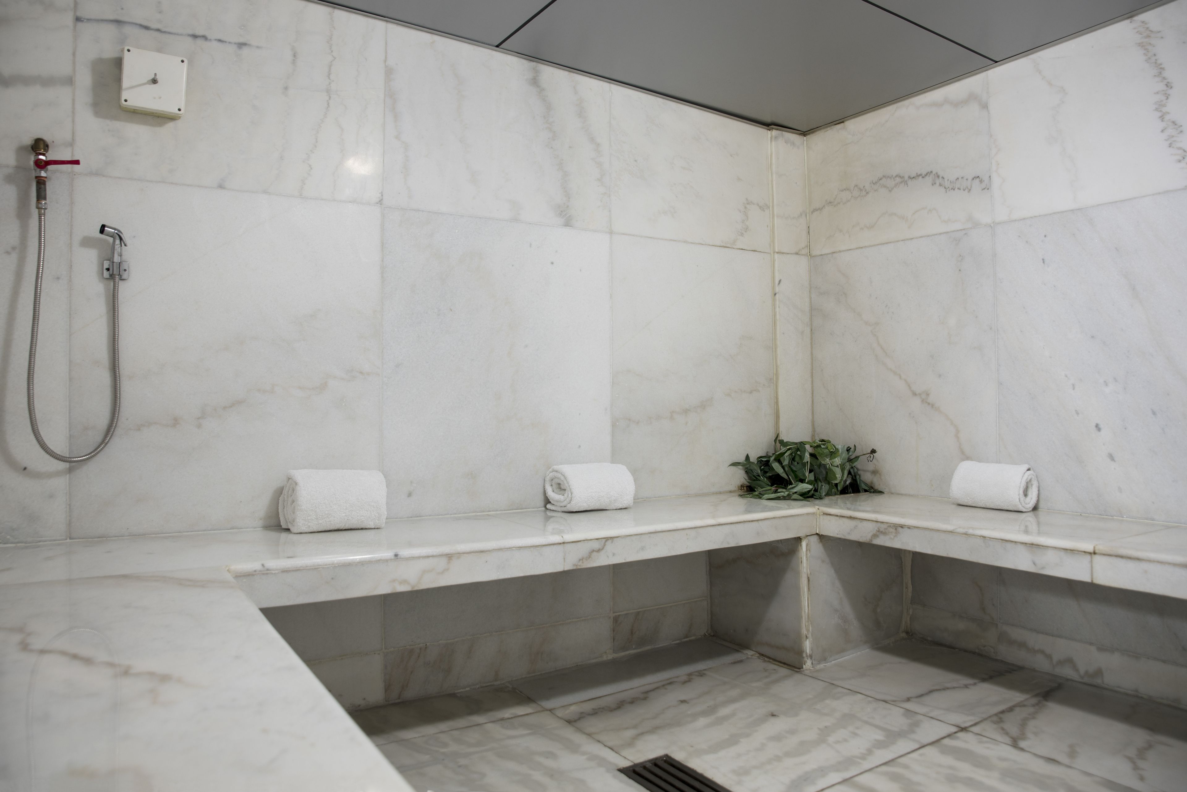 A modern bathroom with white marble tiles, a shower, and two towel racks.