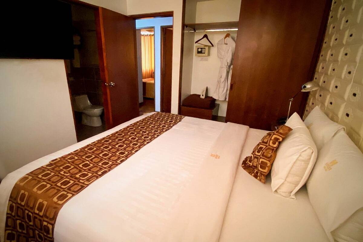 Una habitación de hotel con una cama grande, un armario, un baño y un perchero para abrigos.