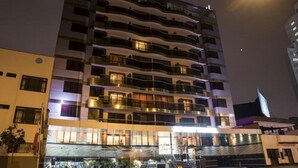 Un hotel a più piani con balconi, un ingresso a livello strada e una facciata ben illuminata.