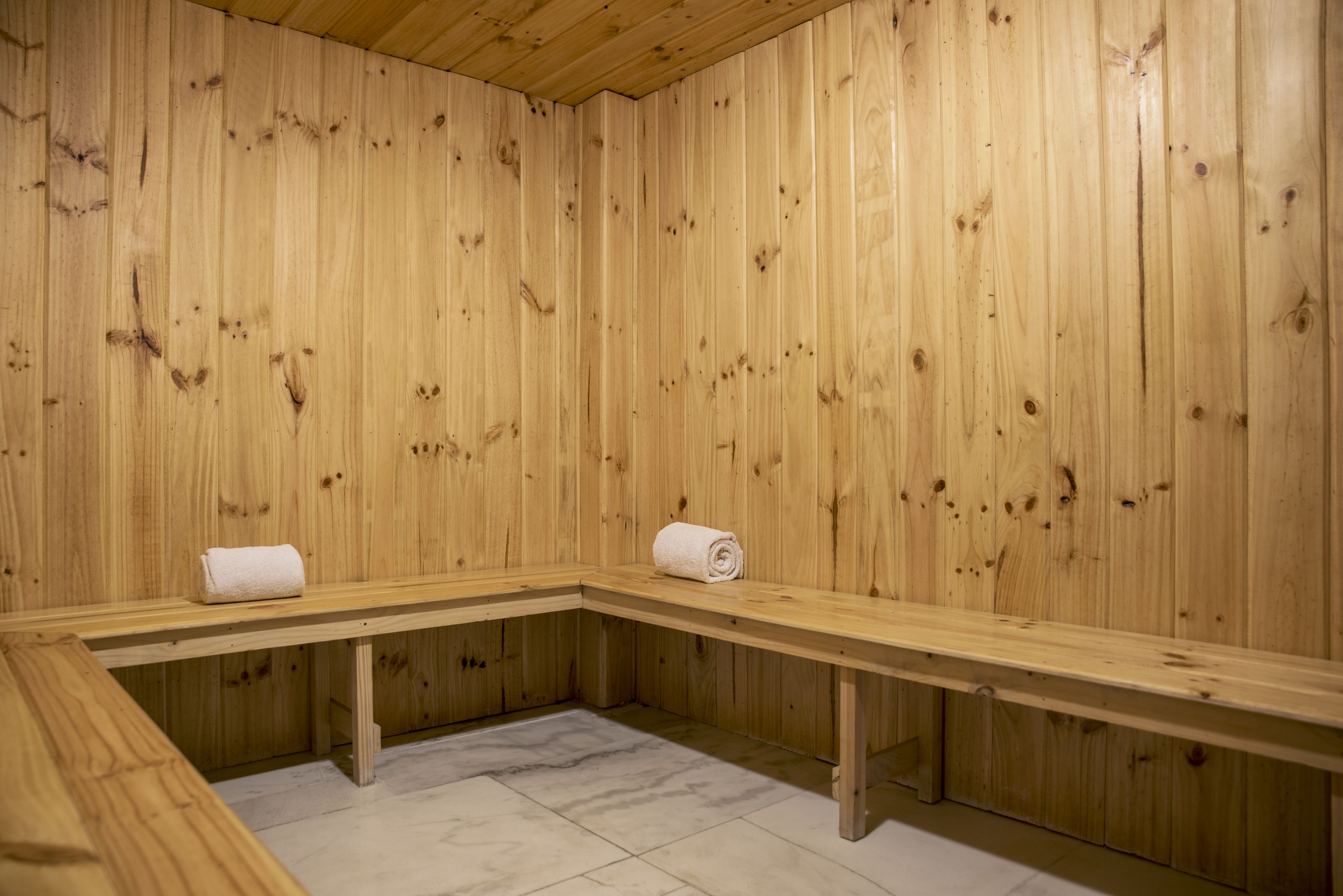 Una sauna de madera con bancos y suelo de mármol.