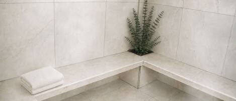 Une salle de bain avec un banc, une plante et une serviette.