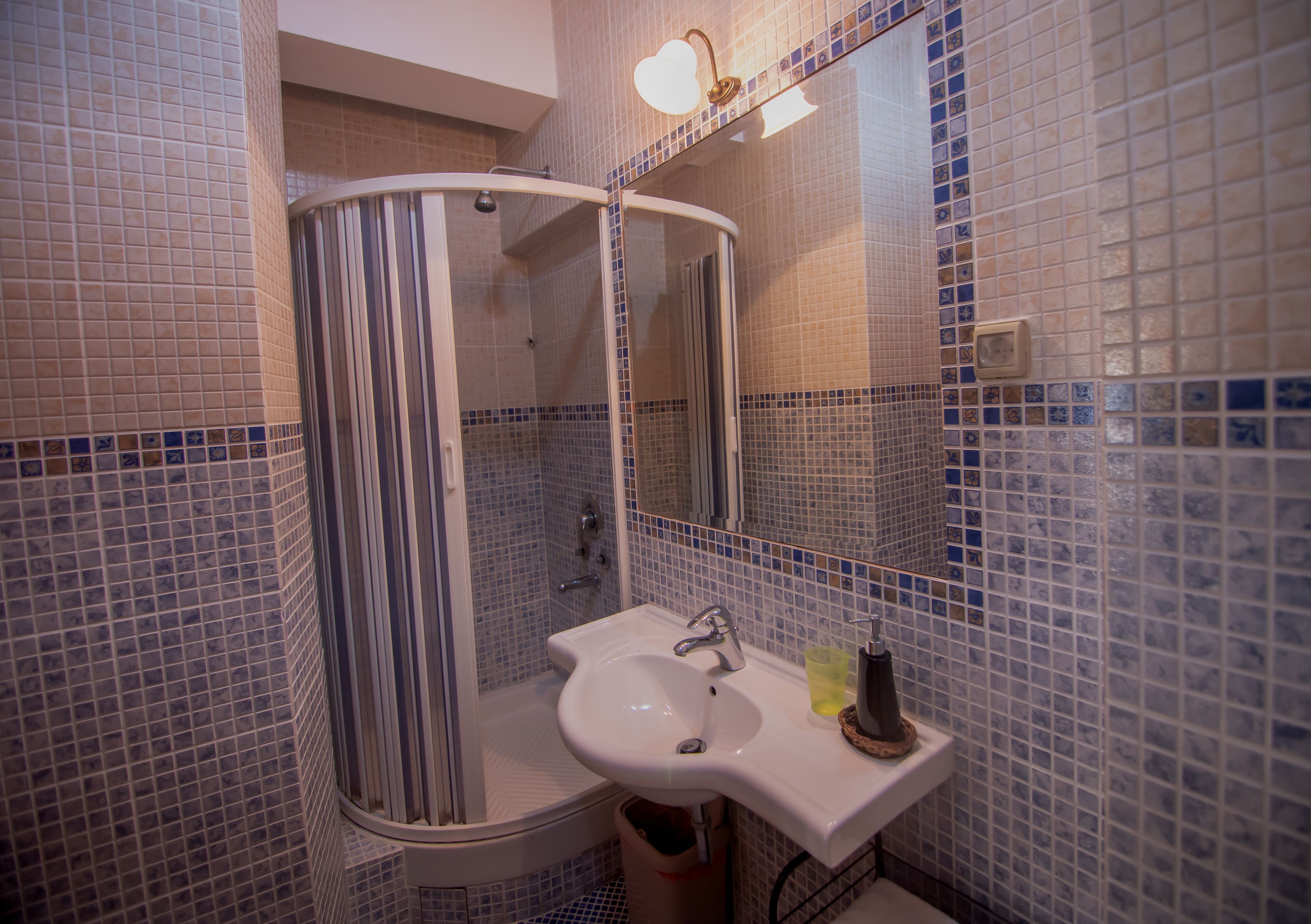 A bathroom with a white sink, a mirror, and a shower with a glass door.