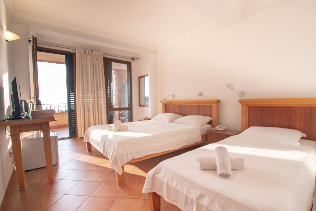 Ein Hotelzimmer mit zwei Betten, einem Schreibtisch, einem Stuhl und einem Fenster mit Vorhängen.