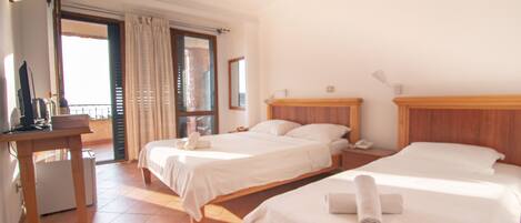 A hotel room with two beds, a desk, a chair, and a window with curtains.
