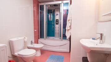 A bathroom with a toilet, bidet, bathtub, and sink.