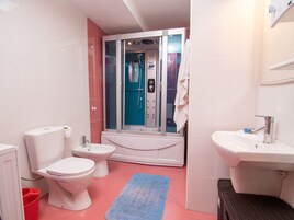 A bathroom with a toilet, bidet, bathtub, and sink.