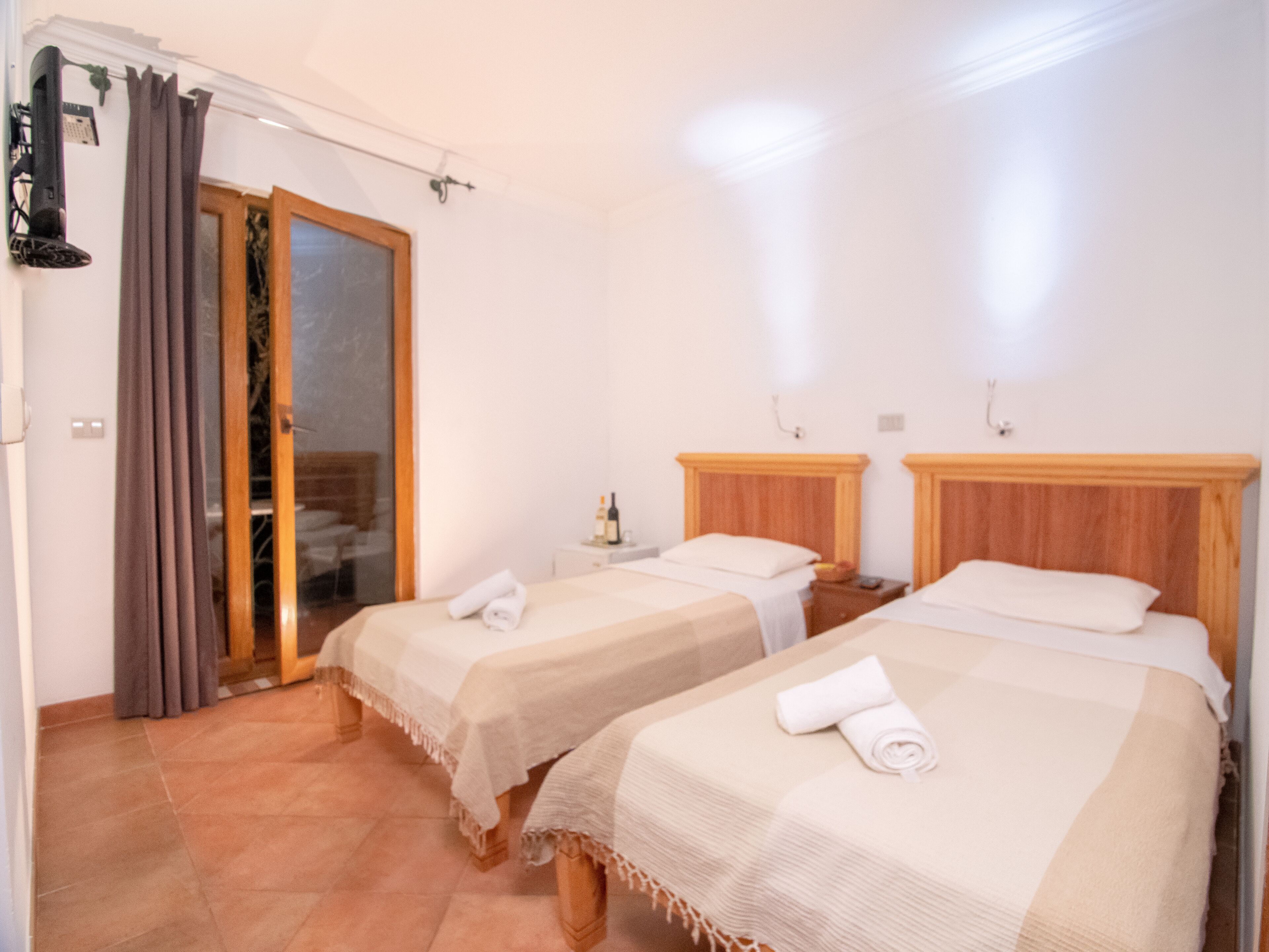 A hotel room with two beds, a bathroom, and a sliding glass door leading to a balcony.