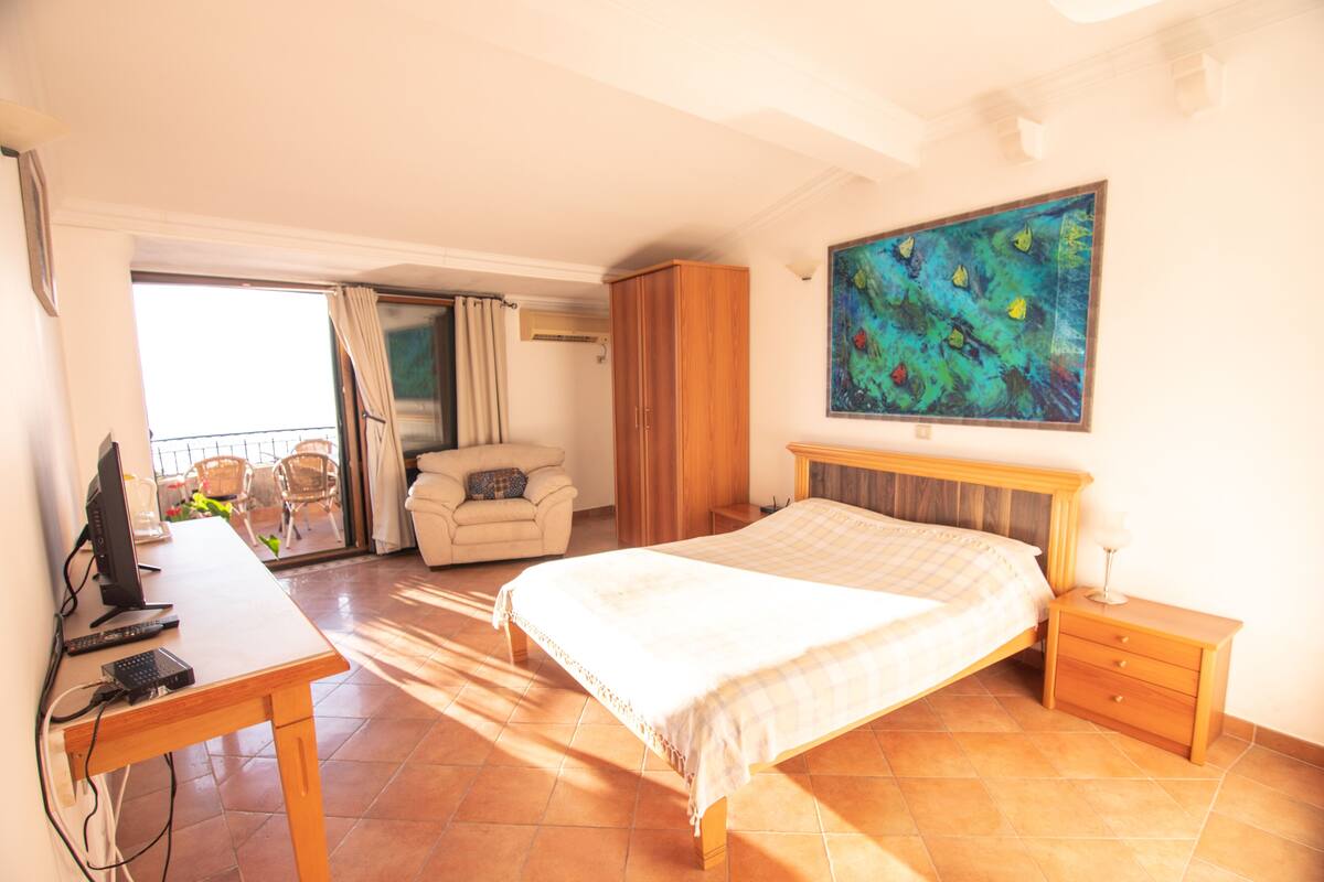 Ein Schlafzimmer mit Bett, Schreibtisch, Stuhl, Kleiderschrank und einem Gemälde an der Wand.
