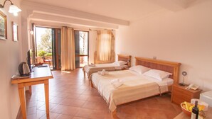 Habitació d'hotel amb dos llits, un escriptori amb una paperera, un telèfon i un bol de fruita.