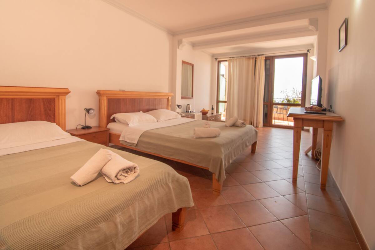 Ein Hotelzimmer mit zwei Betten, einem Schreibtisch mit Computer und einem Balkon mit Blick.