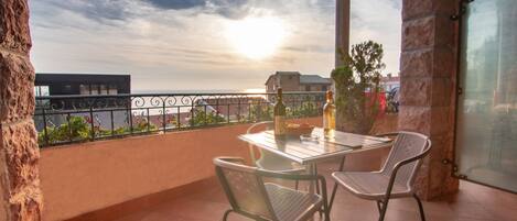 A balcony with a table, two chairs, and two bottles of wine.