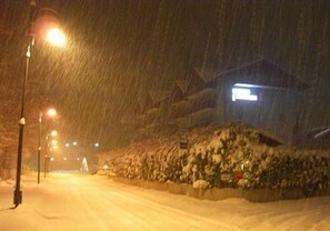 A snow-covered street at night with streetlights and a building in the background. - Hotel Florida (Levico Terme)