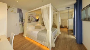 A bedroom with a four-poster bed, a bedside table, a mirror, and a bathroom with a shower and toilet. - Hotel Florida (Levico Terme)