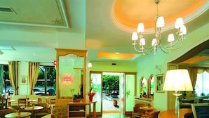 A hotel lobby with a chandelier, seating area, and a reception desk. - Hotel Florida (Levico Terme)
