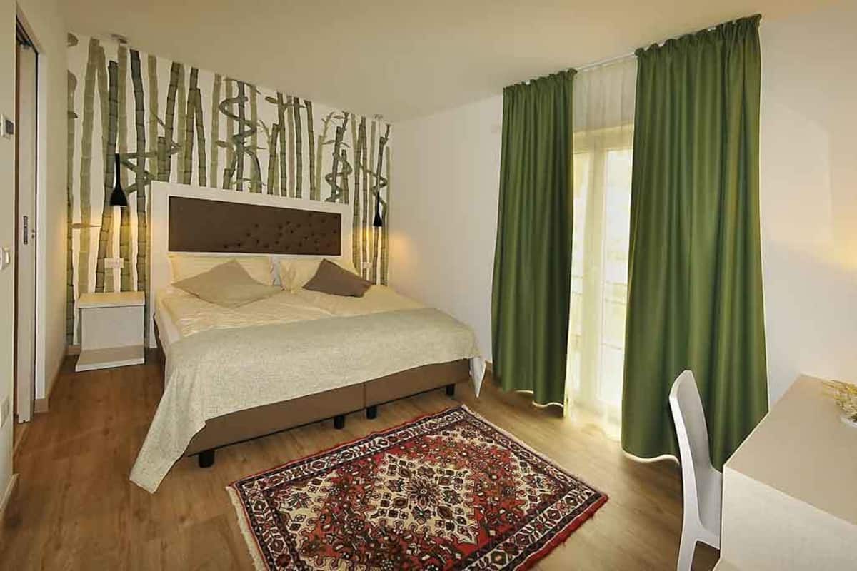 A bedroom with a bed, a desk, and a chair.