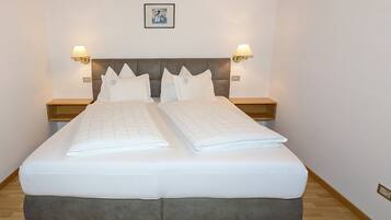 A double bed with a grey headboard, two bedside tables with lamps, and a framed picture on the wall.