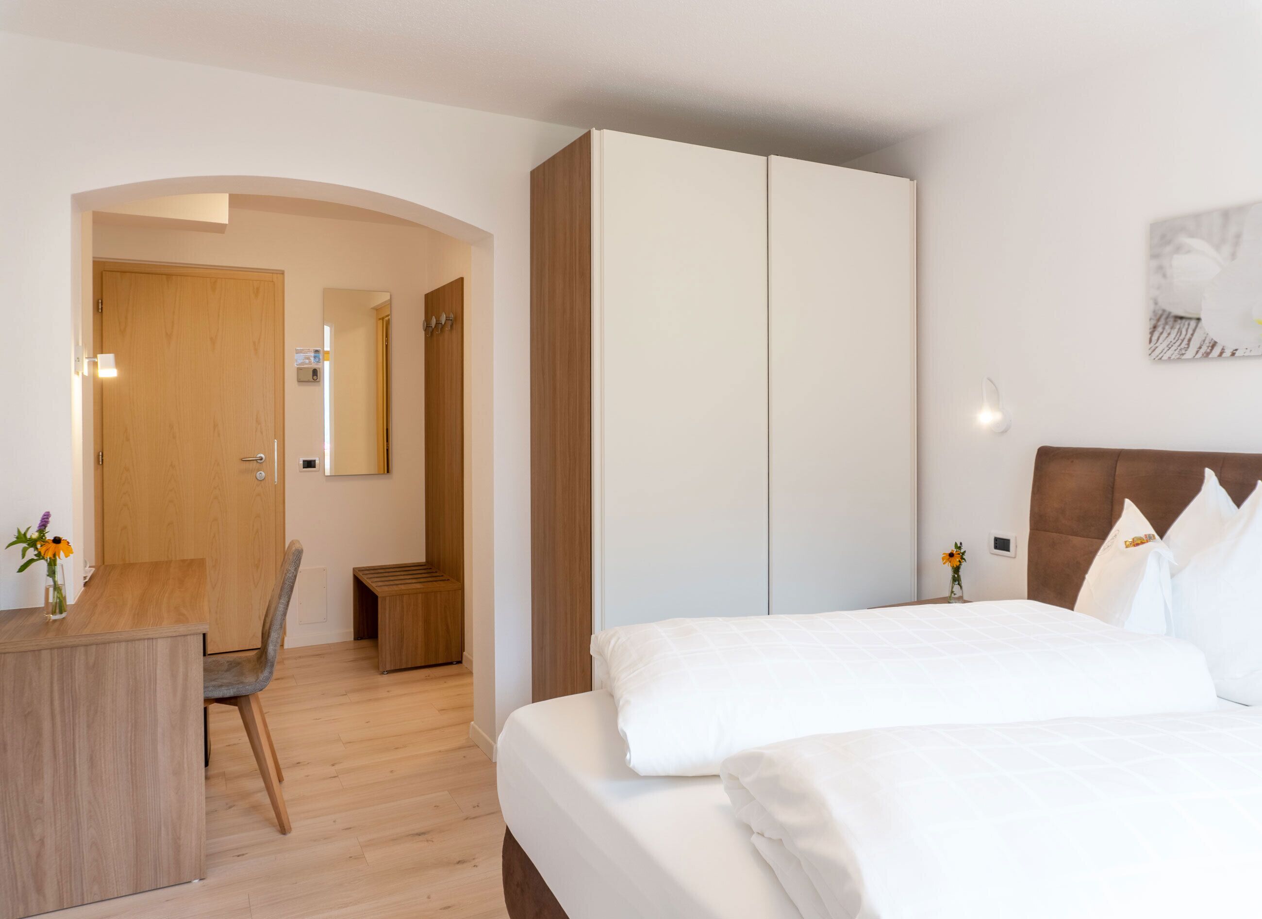 Une chambre d’hôtel avec un lit, un bureau, une armoire et un miroir.